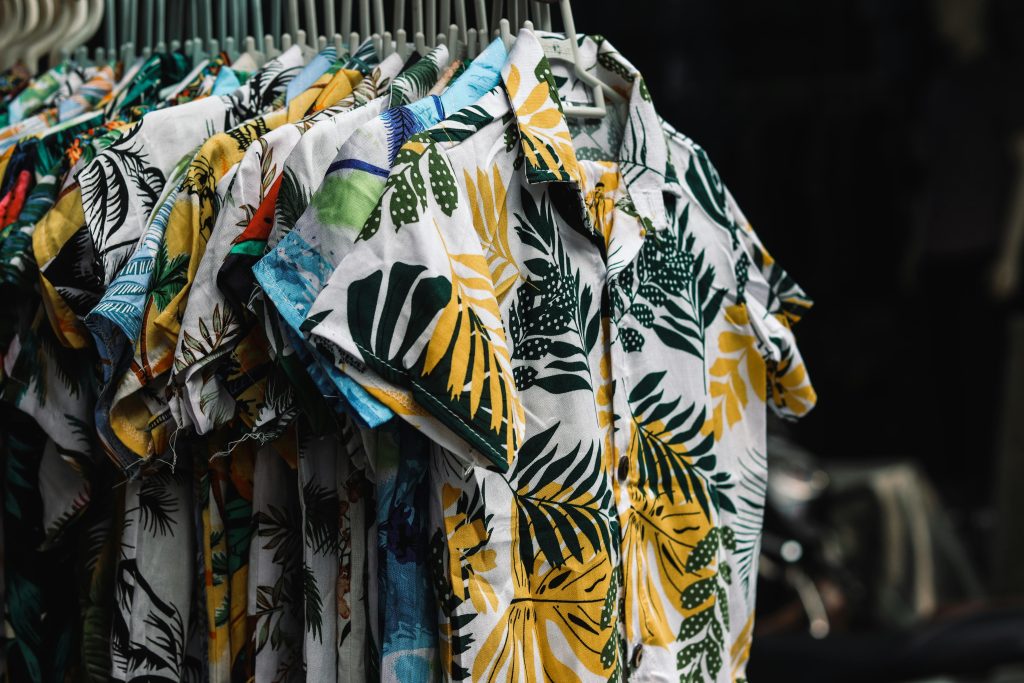 A collection of vibrant tropical print shirts hanging on a rack in a retail store.